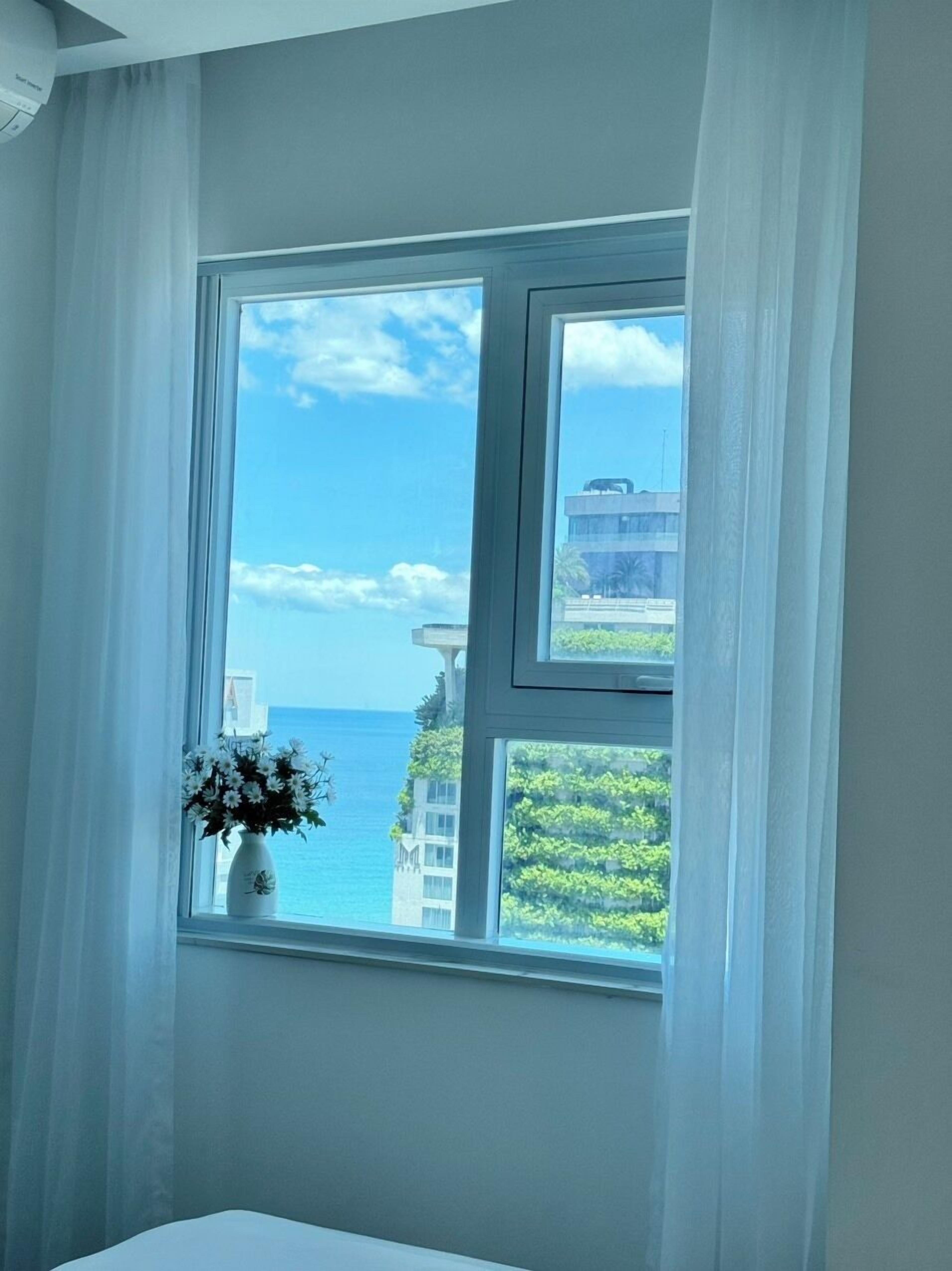 Una habitación con un amplio ventanal que ofrece vistas al mar y a edificios.