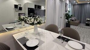 Ein moderner Essbereich mit einem Marmortisch, zwei Stühlen und einer Vase mit weißen Blumen.