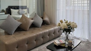 Ein modernes Wohnzimmer mit einer Ledersofa, einem Couchtisch und einem großen Fenster mit transparenten Vorhängen.