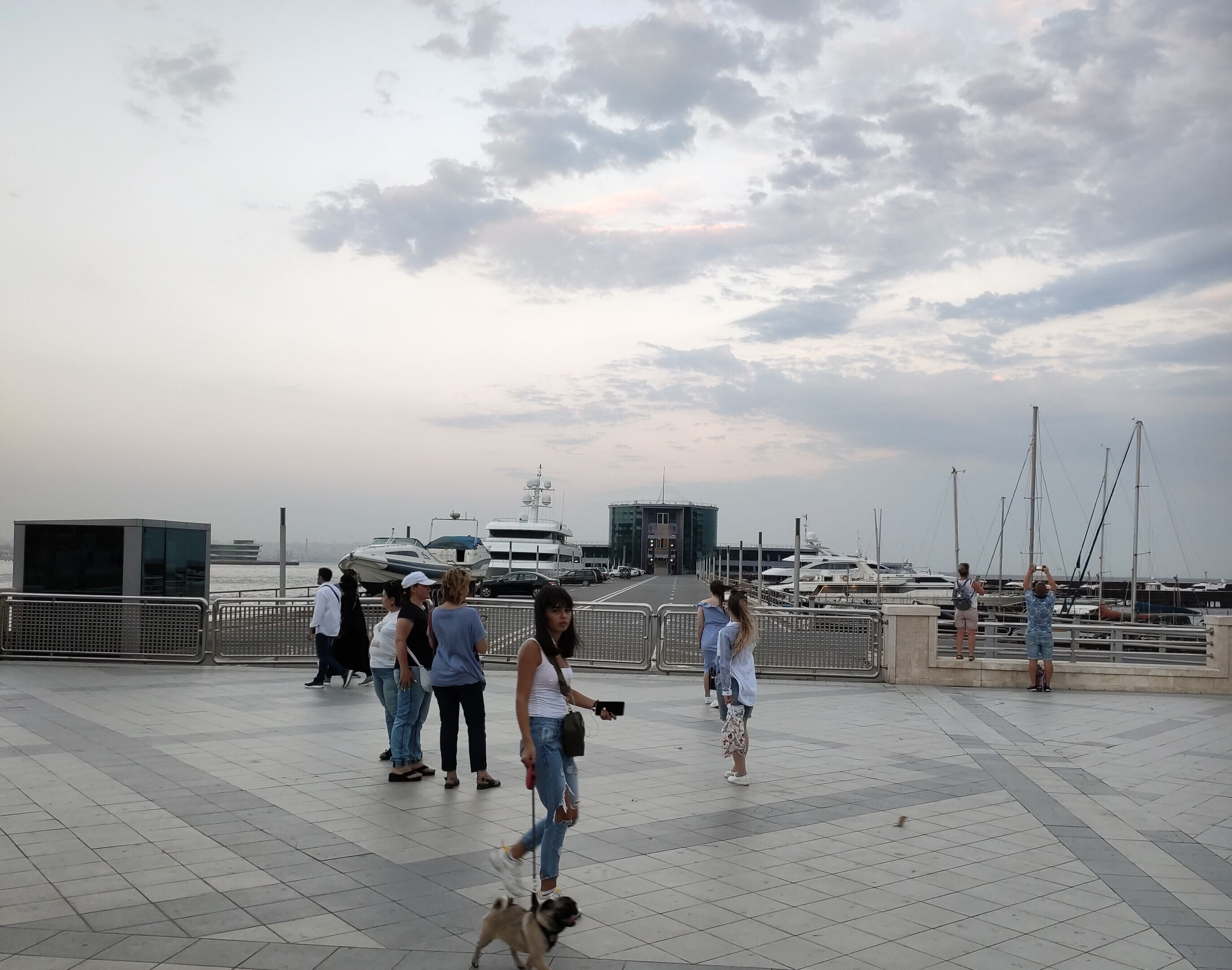 Eine Uferpromenade mit einem Kieselweg, einem Hund und Passanten.