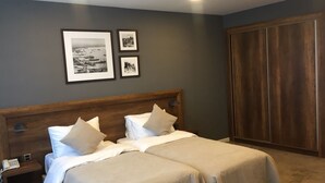 Ein Hotelzimmer mit einem Doppelbett, einem Holzschrank und zwei gerahmten Bildern an der Wand.
