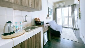 A compact kitchen with a sink, a kettle, and a bread basket. - The Satu Stay Apartement SGV (South Tangerang)