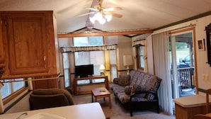 A cozy living room with a television, sofa, and a dining area with a sink.