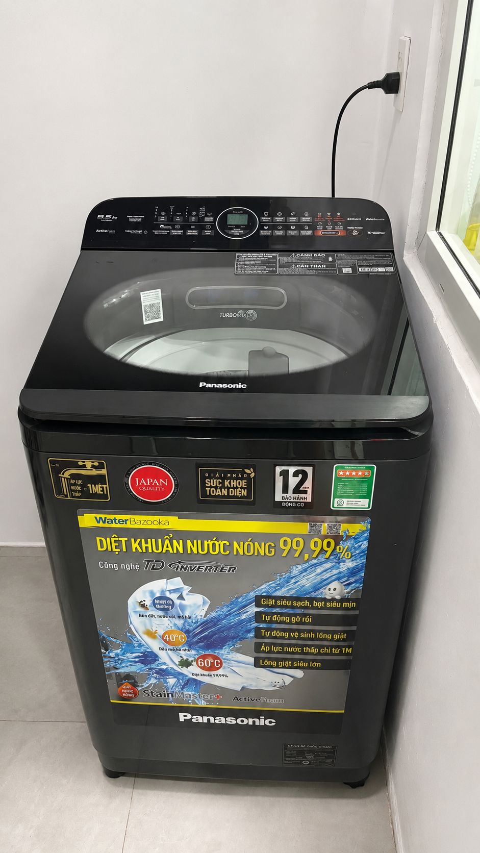 A Panasonic washing machine with a front-loading drum, control panel, and a sticker indicating a 99.99% water efficiency rating.
