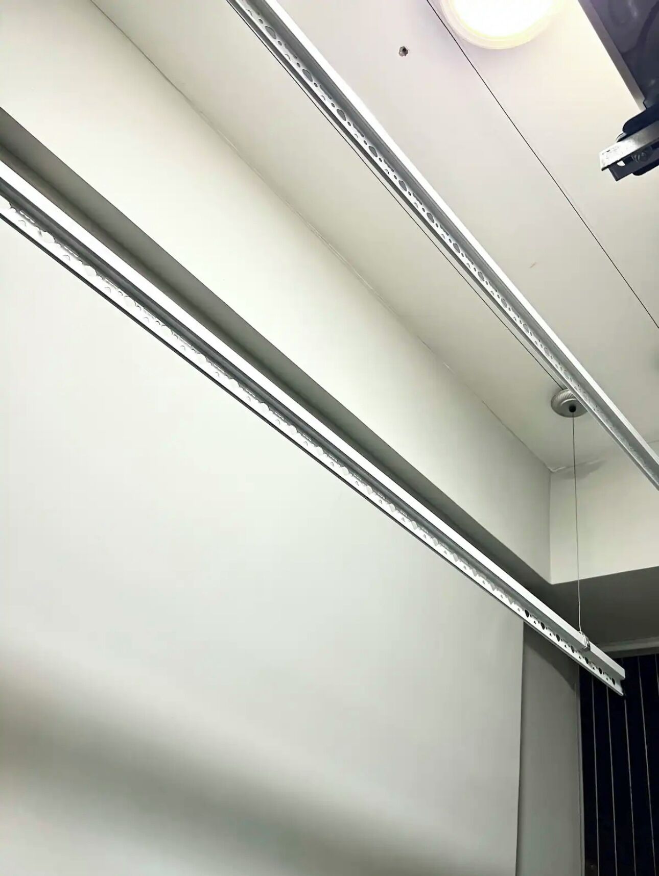 Eine Decke mit Schienenspots und einem Rauchmelder.