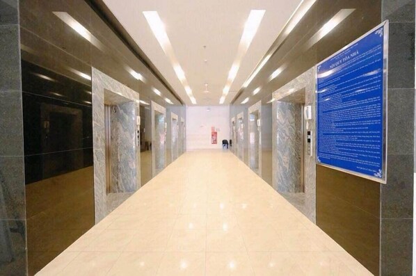 A hallway with marble walls and a tiled floor, leading to a door at the end. - HQH Sea View Apartment (Bac Nha Trang)