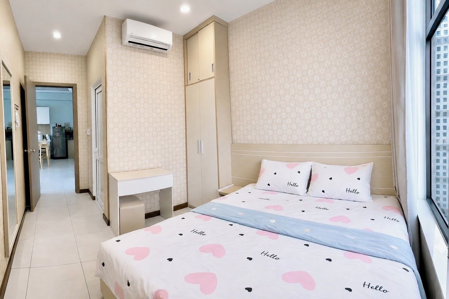 A hotel room with a bed, bedside table, wardrobe, and an air conditioning unit.