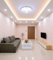 Una sala de estar moderna con sofá, mesa de centro, televisor e iluminación empotrada en el techo.