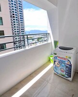 Un balcón con vistas a un paisaje urbano y montañas. Se ve una lavadora Toshiba en el balcón.