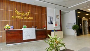 Ein Empfangsschalter mit Holzverkleidung, einem Logo, einer Zimmerpflanze und einem gerahmten Bild an der Wand.