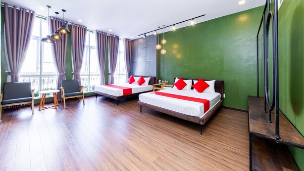 A hotel room with two beds, a sofa, a small table, and a view of the outdoors. - Seven A Hotel (Xuan Huong - Da Lat)