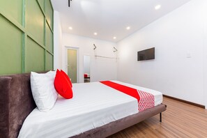Una habitación de hotel moderna con una cama grande, un televisor montado en la pared y una pared de acento verde.