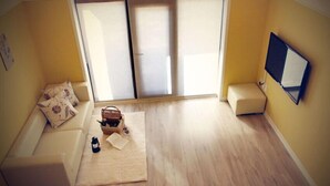 Una habitació amb un sofà, una taula petita amb una cistella i una ampolla, i una porta corredissa.