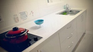 Cuina amb armaris blancs, un rentapla i una cuina vermella.