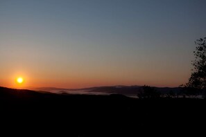 A sunset over a mountainous landscape with silhouettes of trees and hills. - Tuscan farmhouse surrounded by nature and near the sea for 25 people (Riparbella)