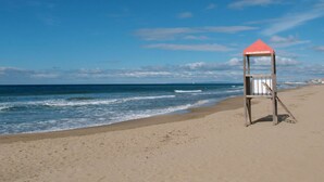 Ein Rettungsturm mit der Aufschrift 'SALVATAGGIO' an einem Strand mit blauem Himmel und ruhiger See.