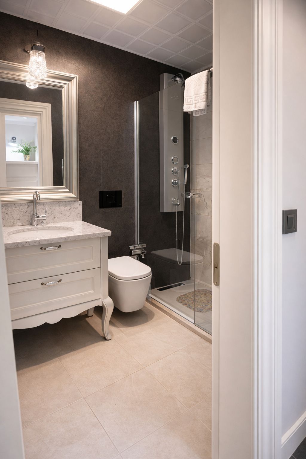 A bathroom with a white vanity, a toilet, a glass shower enclosure, and a large mirror.