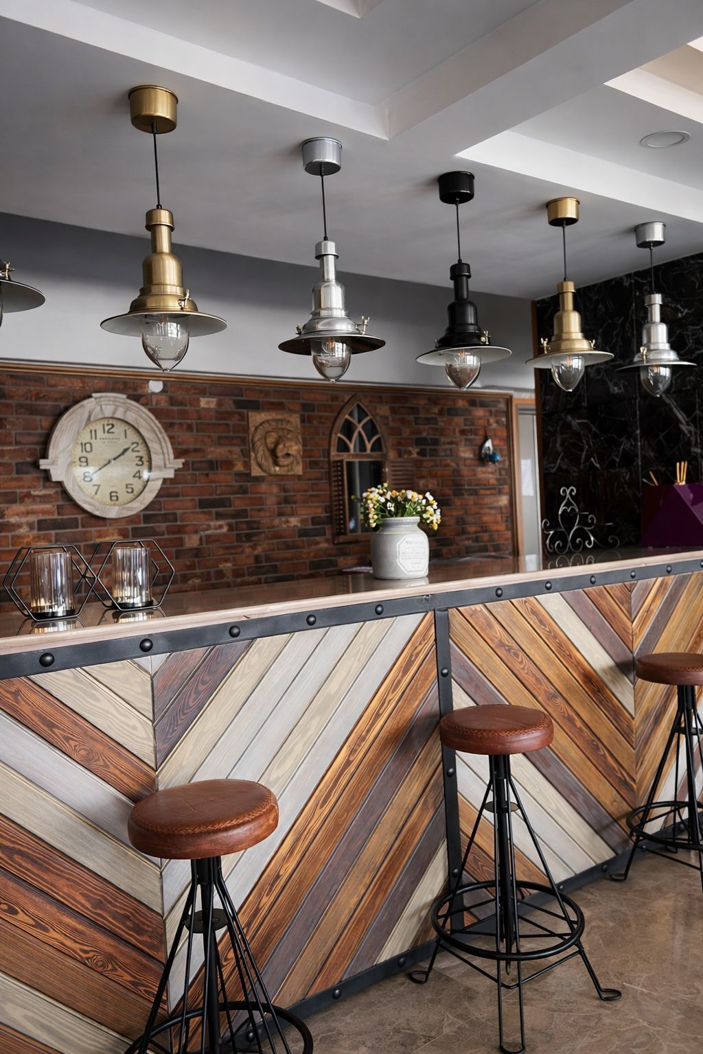 Una zona de bar con pared de madera en patrón de espiga, un reloj y luces colgantes.