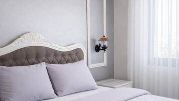 Un dormitorio con cabecera capitonada, cama con ropa de cama estampada, mesita de noche, lámpara de pared y unidad de aire acondicionado.