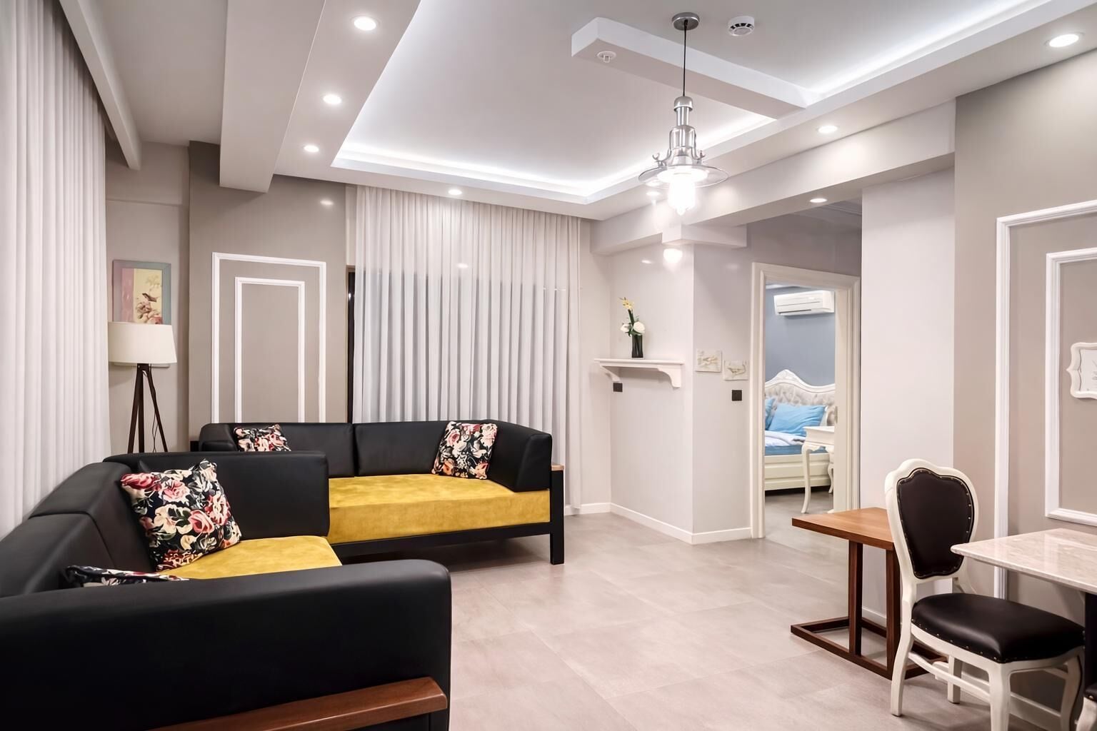 A modern living room with a sofa, a dining table, and a chandelier.