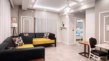 A modern living room with a sofa, a dining table, and a chandelier.