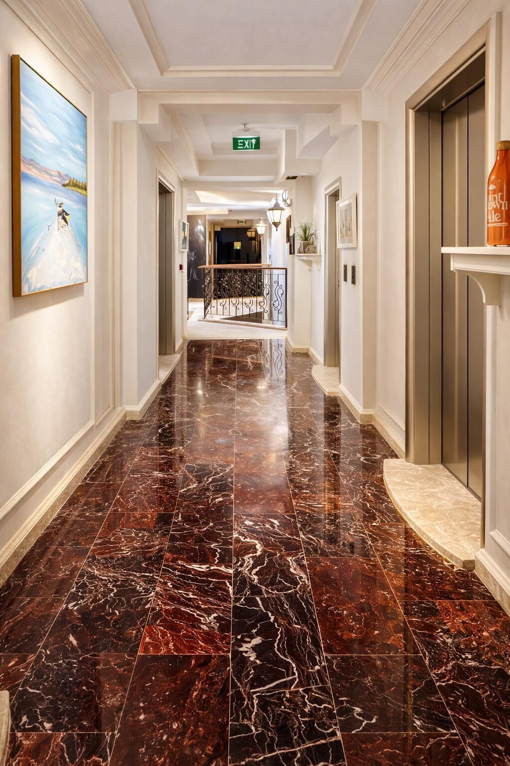 A marble-floored hallway with an exit sign, a painting, and a bottle on a shelf.