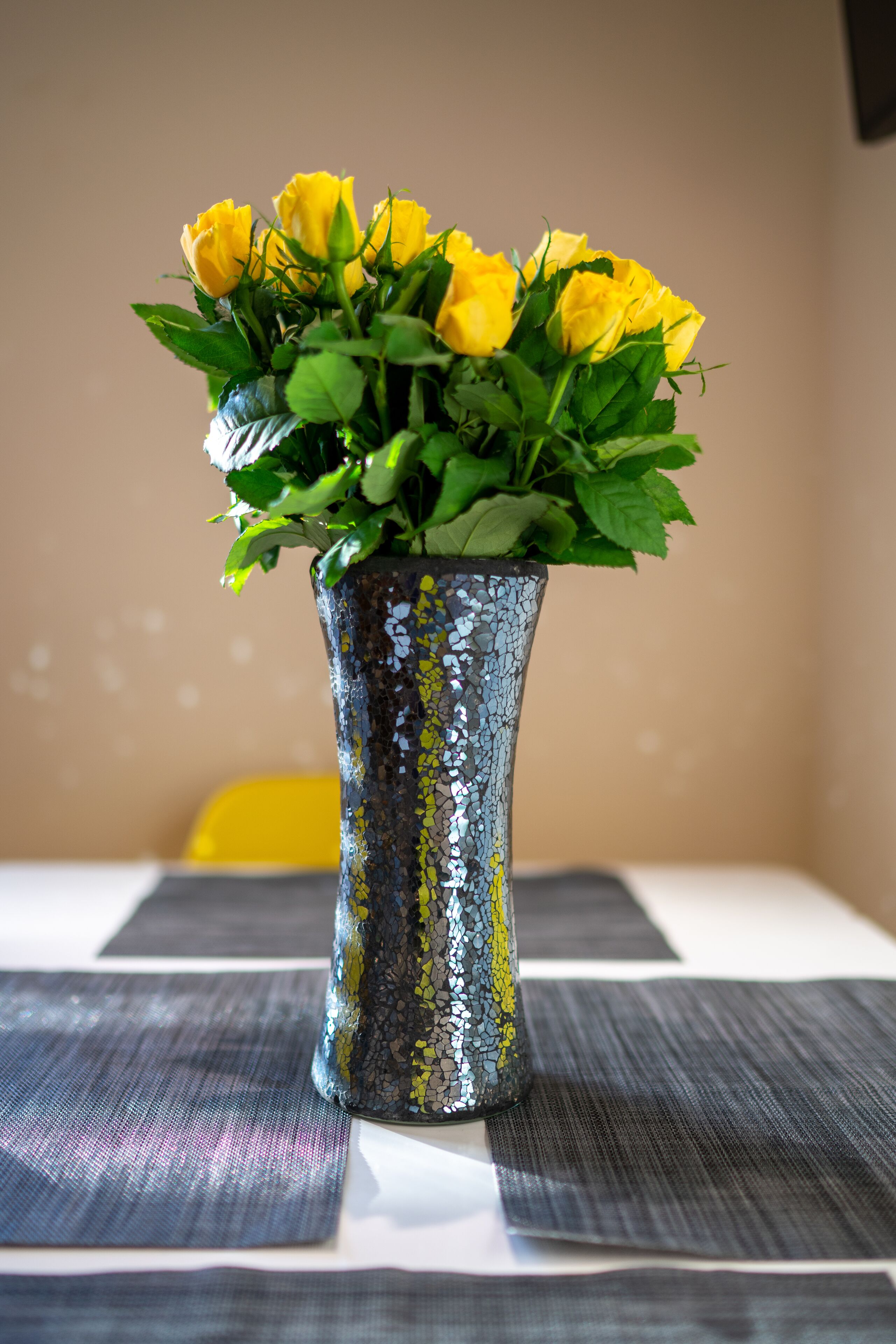 Un jarrón con flores amarillas sobre una mesa.