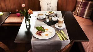 A breakfast setting with a table, a vase of flowers, and a cozy seating area. - Hirschenstube Gästehaus Gehri (Waldkirch)