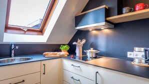 A modern kitchen with a skylight, stainless steel appliances, and a wooden countertop. - Hirschenstube Gästehaus Gehri (Waldkirch)