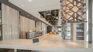 A spacious lobby with a long reception desk, modern seating, and a decorative staircase. - Jin Shi Hu Hotel (Kaohsiung)