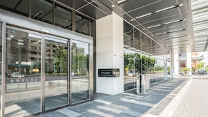 A modern hotel entrance with glass doors, a clear pathway, and a sign indicating the hotel name. - Jin Shi Hu Hotel (Kaohsiung)