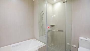 A modern bathroom with a glass-enclosed shower, a white bathtub, and a toilet.