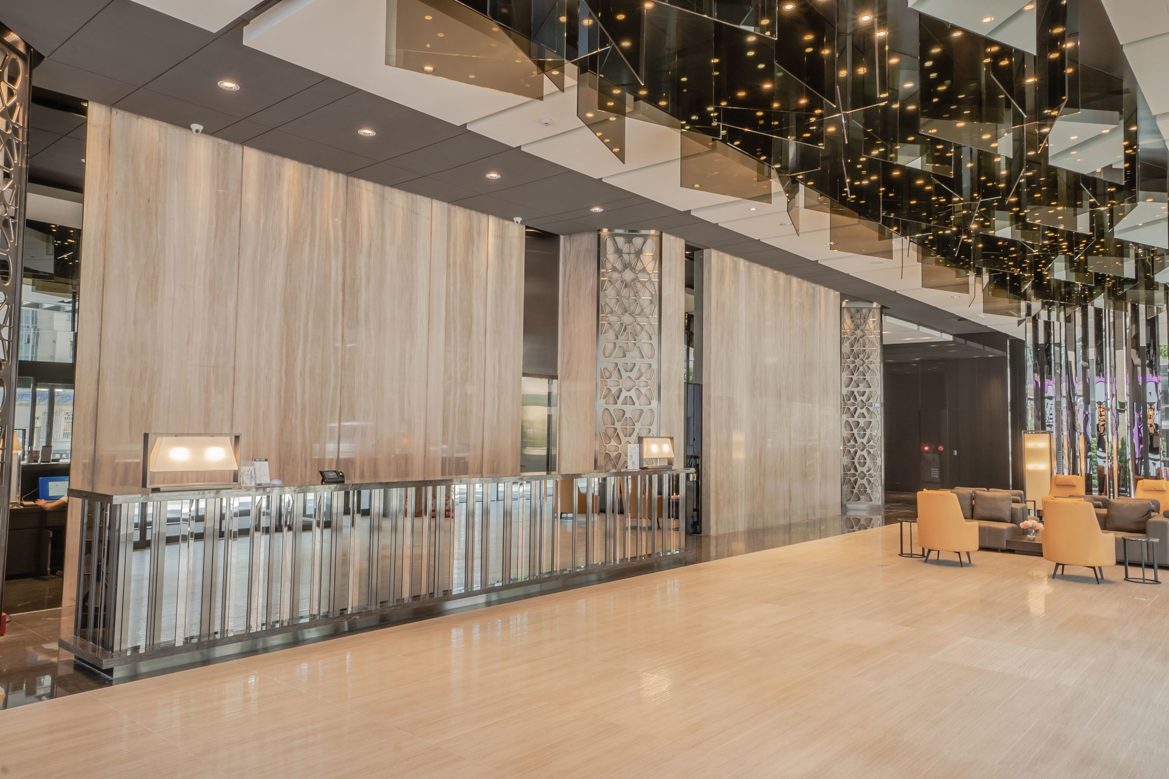 A spacious lobby with a modern design, featuring a reception desk, seating area, and a staircase with glass railings.