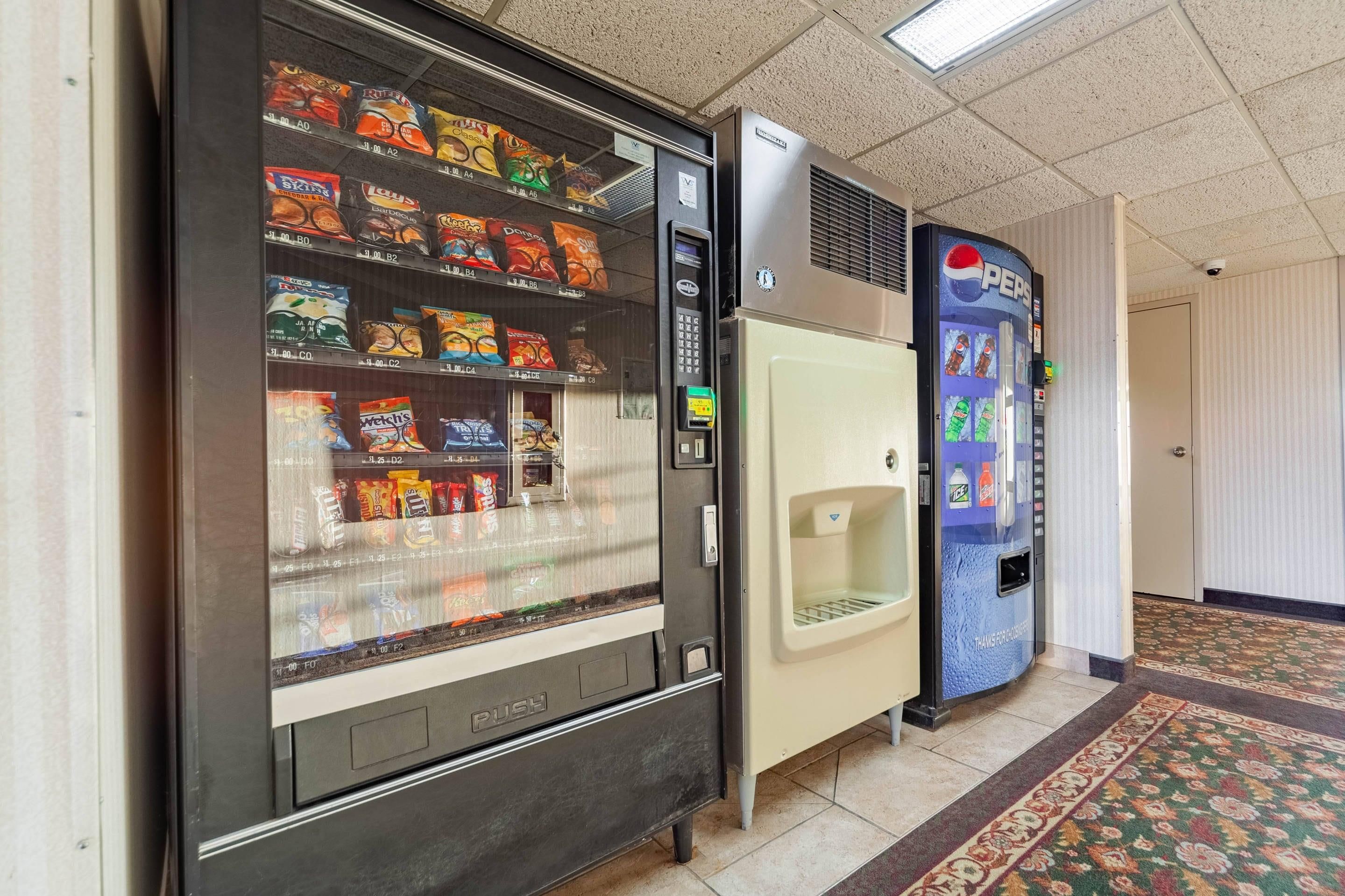 Máquina de vendas com lanches e dispensador de Pepsi em um corredor.