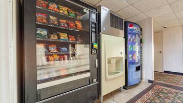 Máquina de vendas com lanches e dispensador de Pepsi em um corredor.