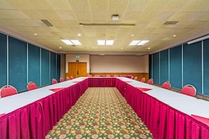 A conference room with a long table, chairs, and a patterned carpet.