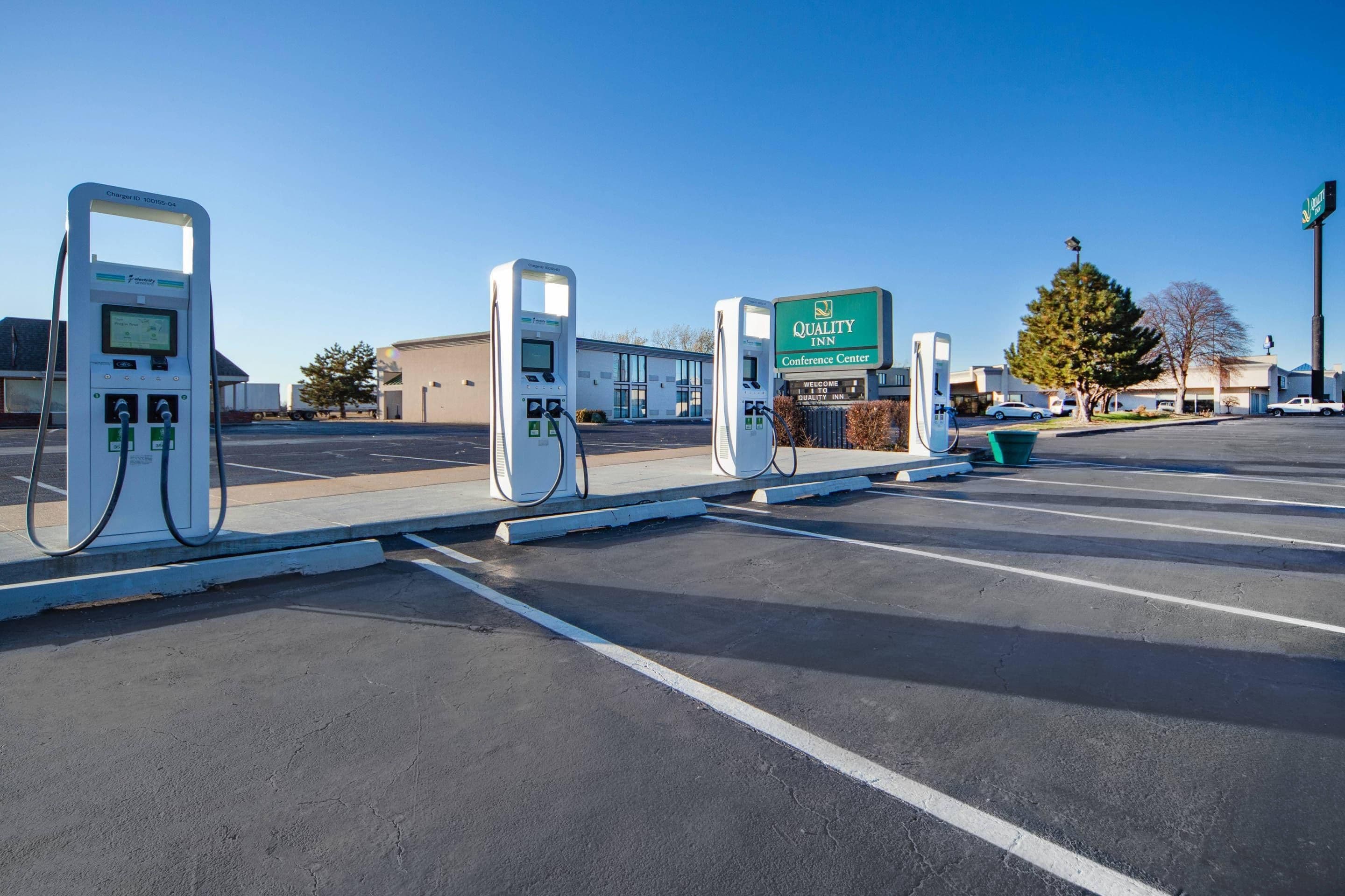 A parking lot with electric vehicle charging stations, a Quality Inn Conference Center sign, and a building in the background.