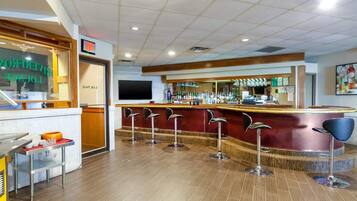 A bar area with stools, a counter, and a television screen.