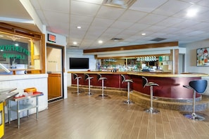 A bar area with stools, a counter, and a television screen.