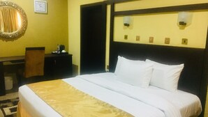 A hotel room with a large bed, a desk, a chair, and a mirror on the wall. - Blue Moon Beach Hotel & Resort (Lagos)