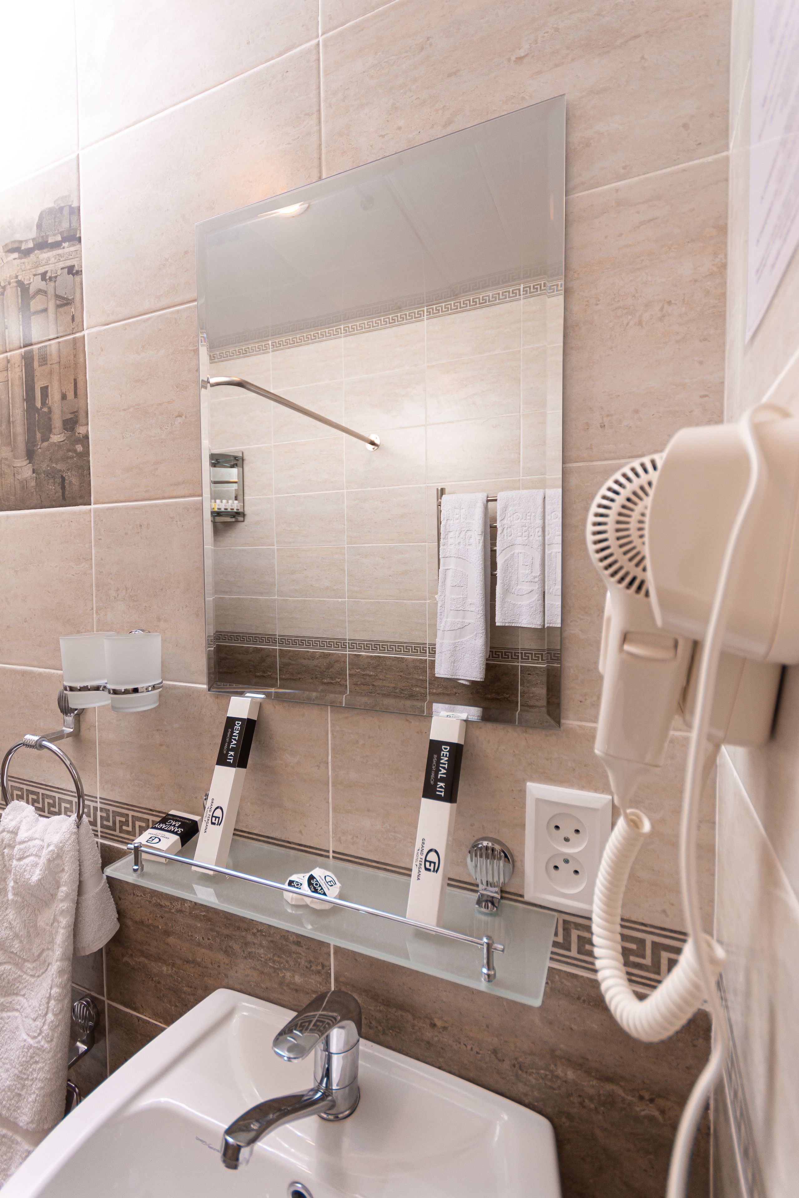 A bathroom with a sink, mirror, hairdryer, and towel rack.