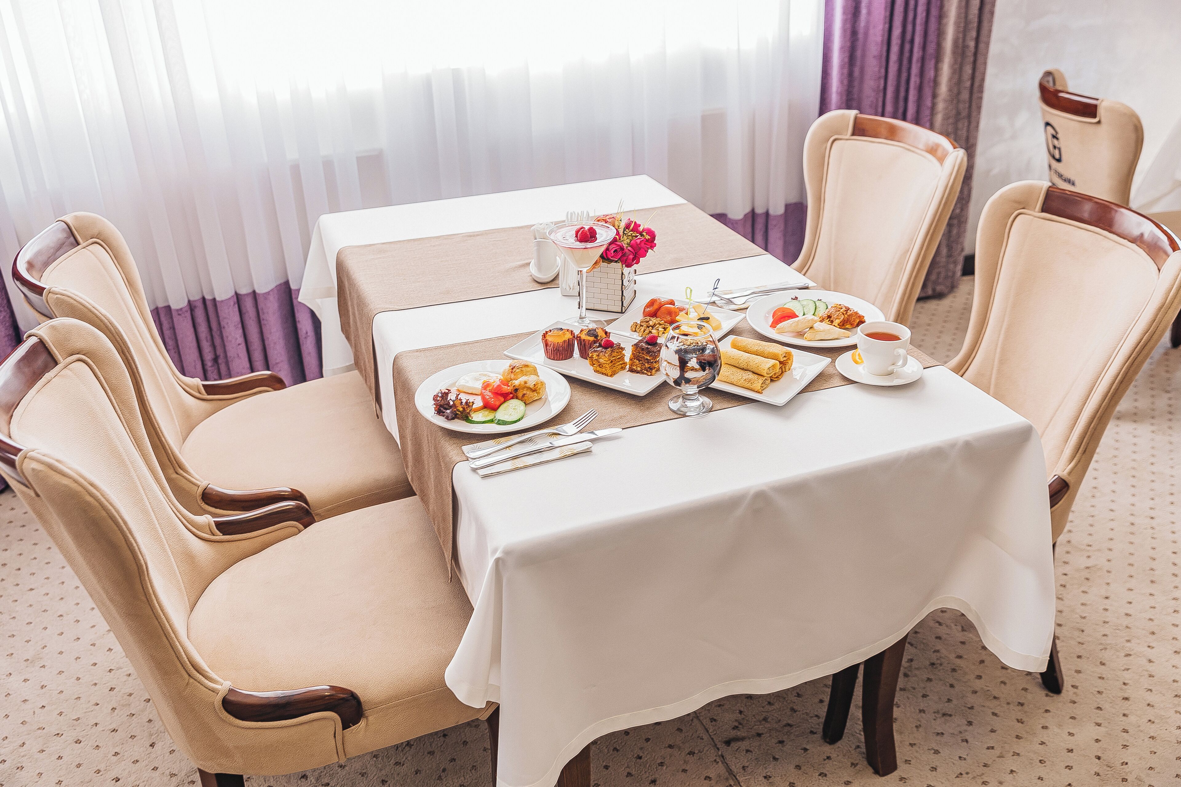 A dining table set with plates of food, a glass of water, and a vase of flowers.