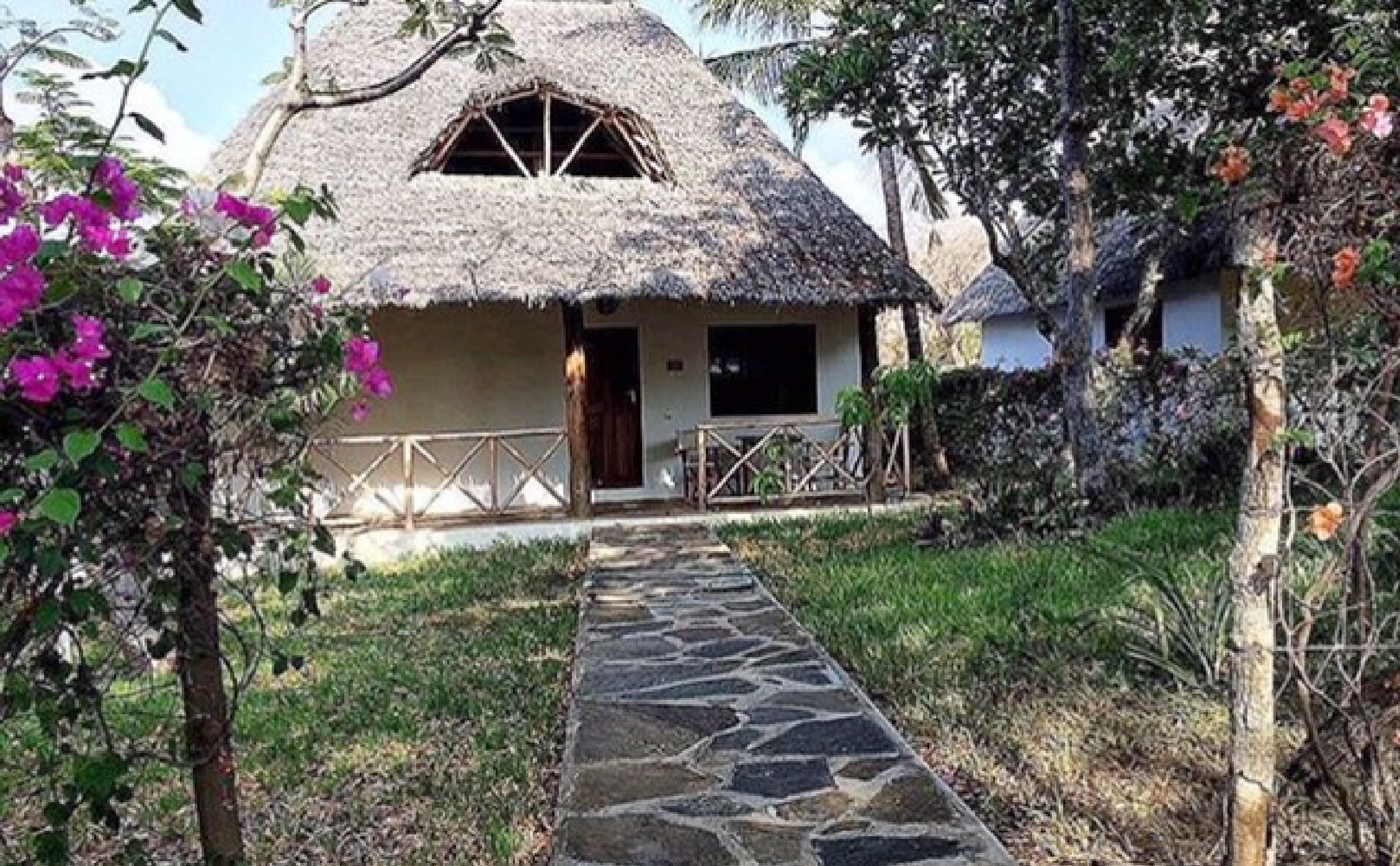 A thatched-roof house with a stone pathway leading to the entrance.