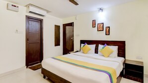 A hotel room with a bed, an air conditioning unit, a wooden door, and a wall-mounted light fixture. - Itsy Hotels Royal Monarch (Gorakhpur)