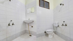 A bathroom with white tiled walls, a white sink, a toilet, and a shower. - Itsy Hotels Royal Monarch (Gorakhpur)