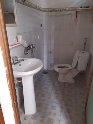 A small, basic bathroom with a sink, toilet, and shower.