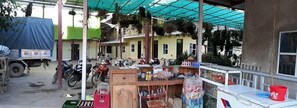 A cluttered outdoor area with a motorcycle, a truck, and a building in the background.