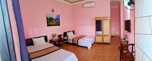 A hotel room with two beds, a wardrobe, a desk, and a television.