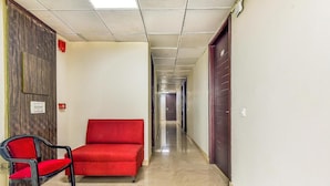 Un pasillo con un sofá rojo, una silla negra y una puerta al final.
