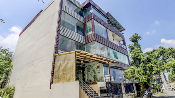 Un hotel moderno con fachada de vidrio, varios pisos y un área de entrada cubierta con escaleras.